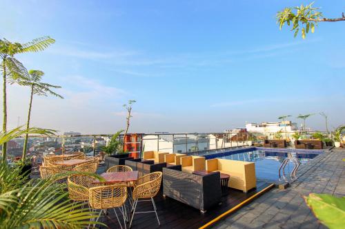 a balcony with chairs and tables and a swimming pool at Hotel FortunaGrande Malioboro Yogyakarta in Yogyakarta