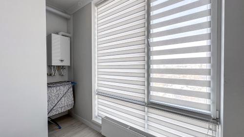 Zimmer mit einem Fenster mit weißen Jalousien in der Unterkunft Tourist New Apartments Avram Iancu in Chişinău