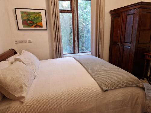 Schlafzimmer mit einem weißen Bett und einem Fenster in der Unterkunft Briar Cottage Guest Suite in Norwood Green, Halifax in Halifax