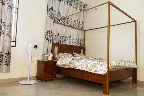 a bedroom with a canopy bed and a fan at Amazoon in Dar es Salaam