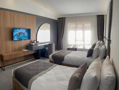 Habitación de hotel con 2 camas y escritorio en Sera Lake Center Hotel, en Akcaabat