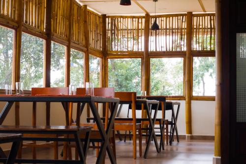 uma sala de jantar com mesas, cadeiras e janelas em GAIRAH RESORT em Mundakāyam