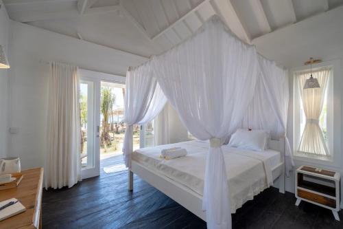 a bedroom with a white bed with a canopy at Paus Putih Hotel in Nusa Lembongan