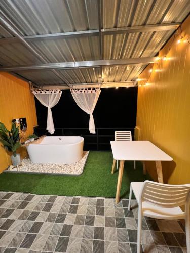 a bathroom with a tub and a table and chairs at บ้านภูไผ่ ไร่ภูไผ่เบิกตะวัน in Ban Nam Phang