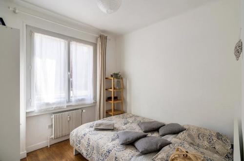 una camera da letto con letto, cuscini e finestra di Lyon Séjour Chambre Cozy pour une personne chez l habitant a Lione
