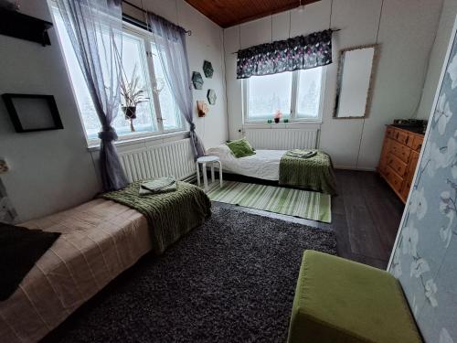 1 dormitorio con 2 camas y 2 ventanas en Northernlight guesthouse, en Kuusamo