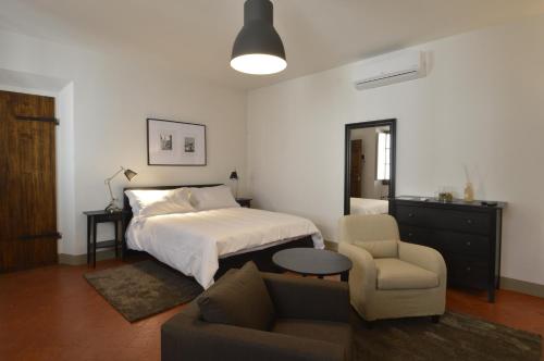 ein Schlafzimmer mit einem Bett, einem Sofa und einem Stuhl in der Unterkunft Toscanelli Residenza d'Epoca in Florenz