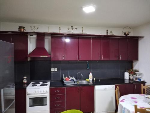 a kitchen with red cabinets and a white stove top oven at Miladinović Bistrica in Bistrica