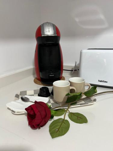 a coffee maker with two cups and a rose on a table at 4 La Laguna, céntrico y acogedor in Las Lagunas