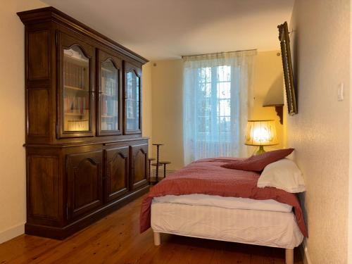 ein Schlafzimmer mit einem großen Holzschrank und einem Bett in der Unterkunft Le Colas in Saint-Maurice-de-Tavernole