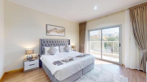 a bedroom with a large bed and a large window at Primestay - VILLA 4 - JVC in Dubai