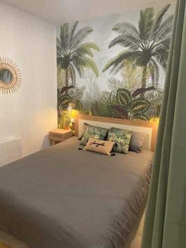 ein Bett in einem Schlafzimmer mit Palmen an der Wand in der Unterkunft Escapades L'Isloises au cœur de L'Isle-sur-la-Sorgue. in LʼIsle-sur-la-Sorgue