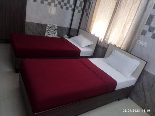 two beds in a room with red and white sheets at Surya's Guest House in Chennai