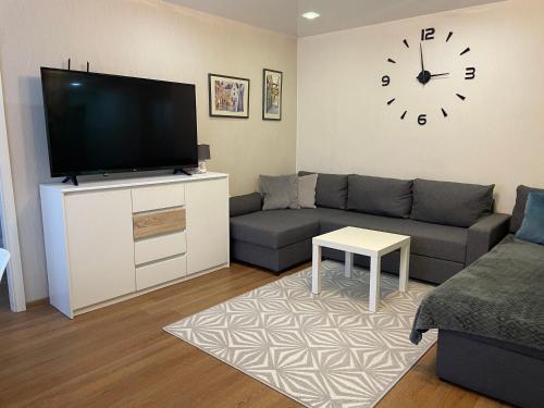 uma sala de estar com um sofá e um relógio na parede em Like a home Linda Apartment em Narva