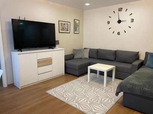 a living room with a couch and a clock on the wall at Like a home Linda Apartment in Narva