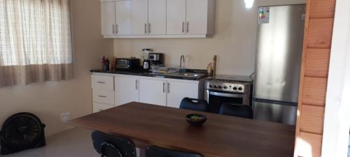 uma cozinha com armários brancos e uma mesa de madeira com cadeiras em Refugio familiar em Pucón