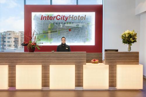 a man sitting at a table with a sign on it at IntercityHotel Enschede in Enschede