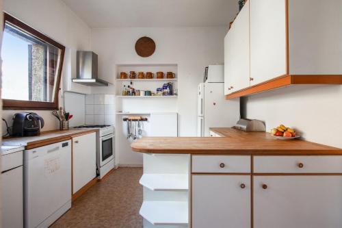 a kitchen with white cabinets and a wooden counter top at Chalet confortable à Briançon avec vue sur montagne in Briançon