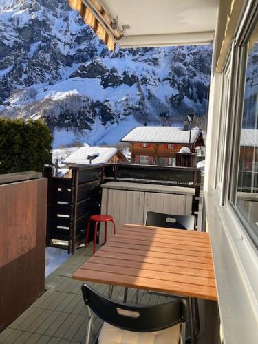 a table and chairs on a balcony with a mountain mural at Sunny-Nest, Garden Apartment in Leukerbad