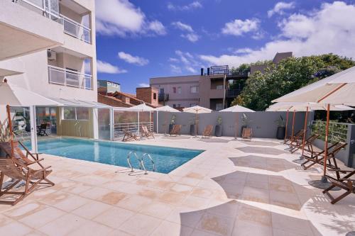 a swimming pool with chairs and umbrellas next to a building at Terrazas Ostende - Apart Hotel in Ostende