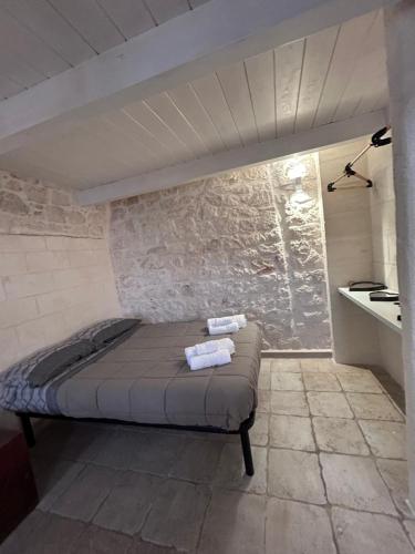 un lit dans une chambre avec un mur en pierre dans l'établissement LA 13 guest house, à Ostuni