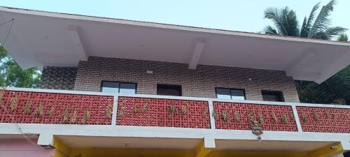 a building with a red fence on a balcony at Mahalaxmi Guest House in Gokarna