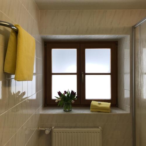 a bathroom with a window and a vase of flowers at Gästehaus Hotel Maria Theresia in Schliersee