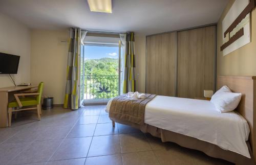 a bedroom with a bed and a desk and a window at The Originals Boutique, Hotel l'Occitan, Aubagne in La Destrousse