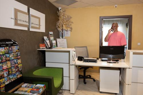 a man talking on a phone in an office at The Originals Boutique, Hotel l'Occitan, Aubagne in La Destrousse