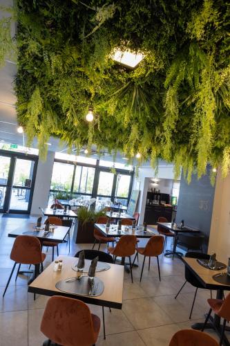 a restaurant with tables and chairs and a ceiling with plants at The Originals Boutique, Hotel l'Occitan, Aubagne in La Destrousse