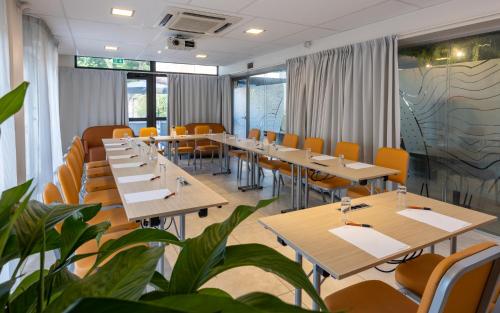 a restaurant with tables and chairs and plants at The Originals Boutique, Hotel l'Occitan, Aubagne in La Destrousse