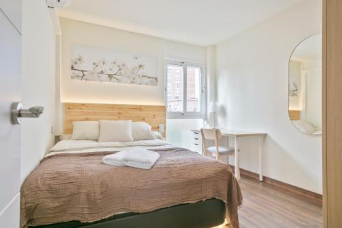 een slaapkamer met een bed, een bureau en een spiegel bij Apartamento soleado y acogedor in Barcelona