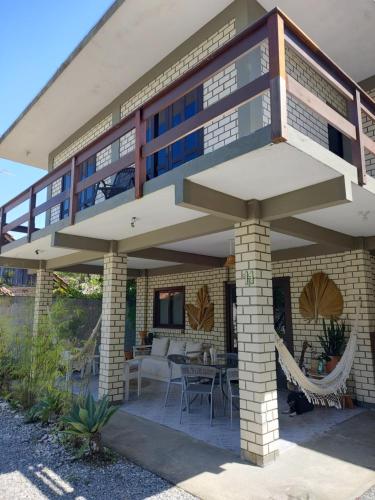 a house with a balcony with a table at Residencial e Pousada Acauan in Guarda do Embaú