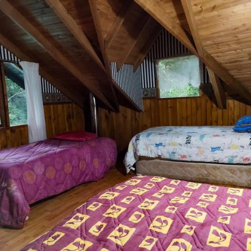 a room with two beds in a attic at Cabaña Pachamama in Caburgua