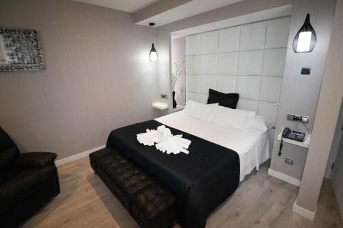 a hotel room with a bed with two white flowers on it at Hoteles Urbanos N Avenida de España in Fuenlabrada