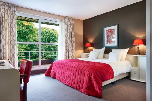 a bedroom with a bed with a red blanket and a window at Hotel Martensplek in Tiendeveen