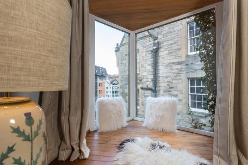 een kamer met een groot raam met witte harige stoelen bij The Converted Stables - A Characterful Mews House in Edinburgh