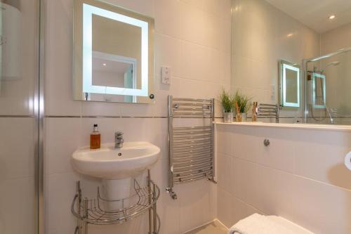 een witte badkamer met een wastafel en een spiegel bij The Converted Stables - A Characterful Mews House in Edinburgh