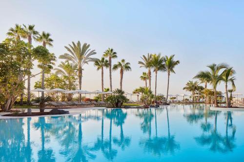 una gran piscina con palmeras en el fondo en Tivoli La Caleta Resort, en Adeje
