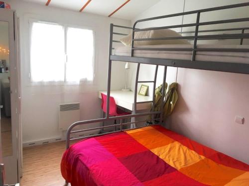 a bedroom with a bunk bed with a colorful blanket at Chalet au bord du Lac de Guerlédan in Caurel