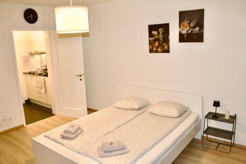 a white bedroom with a bed with two towels on it at Apartments zum Bühlhof (Julie) in Zürich