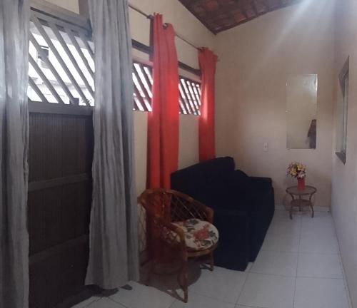 sala de estar con sofá negro y cortinas rojas en CASA DE TEMPORADA, en Barreirinhas