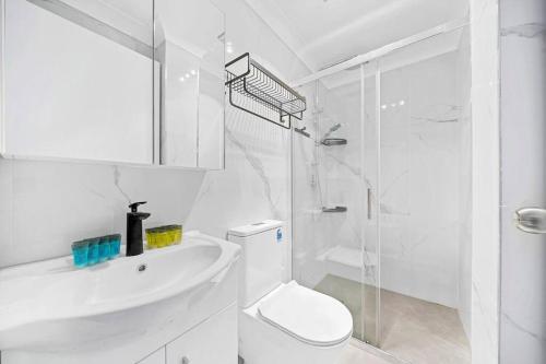 y baño blanco con aseo y ducha. en Modern 4B2B house@Glebe en Sídney