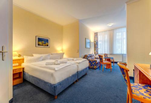 a hotel room with a large bed and a chair at Haus Seeblick Hotel Garni & Ferienwohnungen in Zinnowitz
