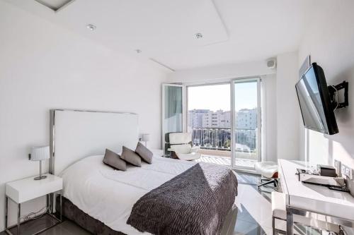 ein weißes Schlafzimmer mit einem Bett, einem Schreibtisch und einem TV in der Unterkunft Luxueux appartement à 50 m de la Croisette in Cannes