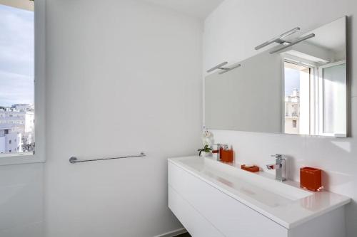 ein weißes Badezimmer mit einem Waschbecken und einem Spiegel in der Unterkunft Luxueux appartement à 50 m de la Croisette in Cannes