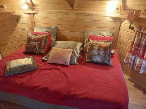 a bed with red sheets and pillows in a room at Kota Finlandais Vacances Insolites in Véria