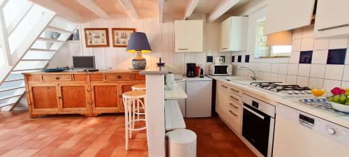 a kitchen with white cabinets and a stove top oven at Petite maison de village avec étage in La Couarde-sur-Mer