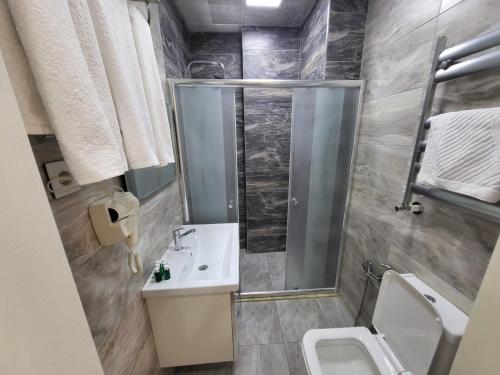 uma casa de banho com um chuveiro, um lavatório e um WC. em Venera Hotel em Baku