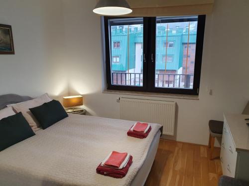 ein Schlafzimmer mit einem Bett mit zwei roten Handtüchern darauf in der Unterkunft Apartman Relax Bjelašnica in Trnovo